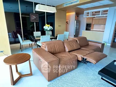 Luxurious modern living room with leather sofa and elegant dining area in open layout apartment.