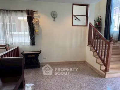 Charming interior with wooden staircase and cozy seating area, perfect for a welcoming home atmosphere.