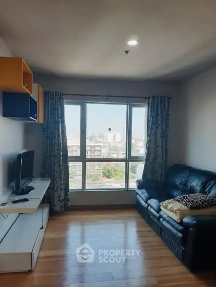 Modern living room with large window and city view, featuring sleek furniture and wooden flooring.