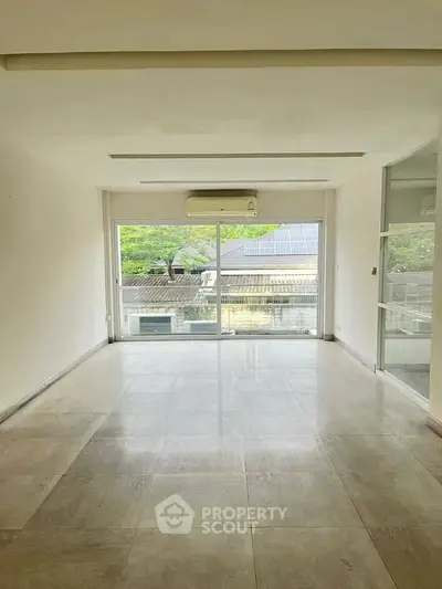 Spacious living room with large windows and modern air conditioning unit.