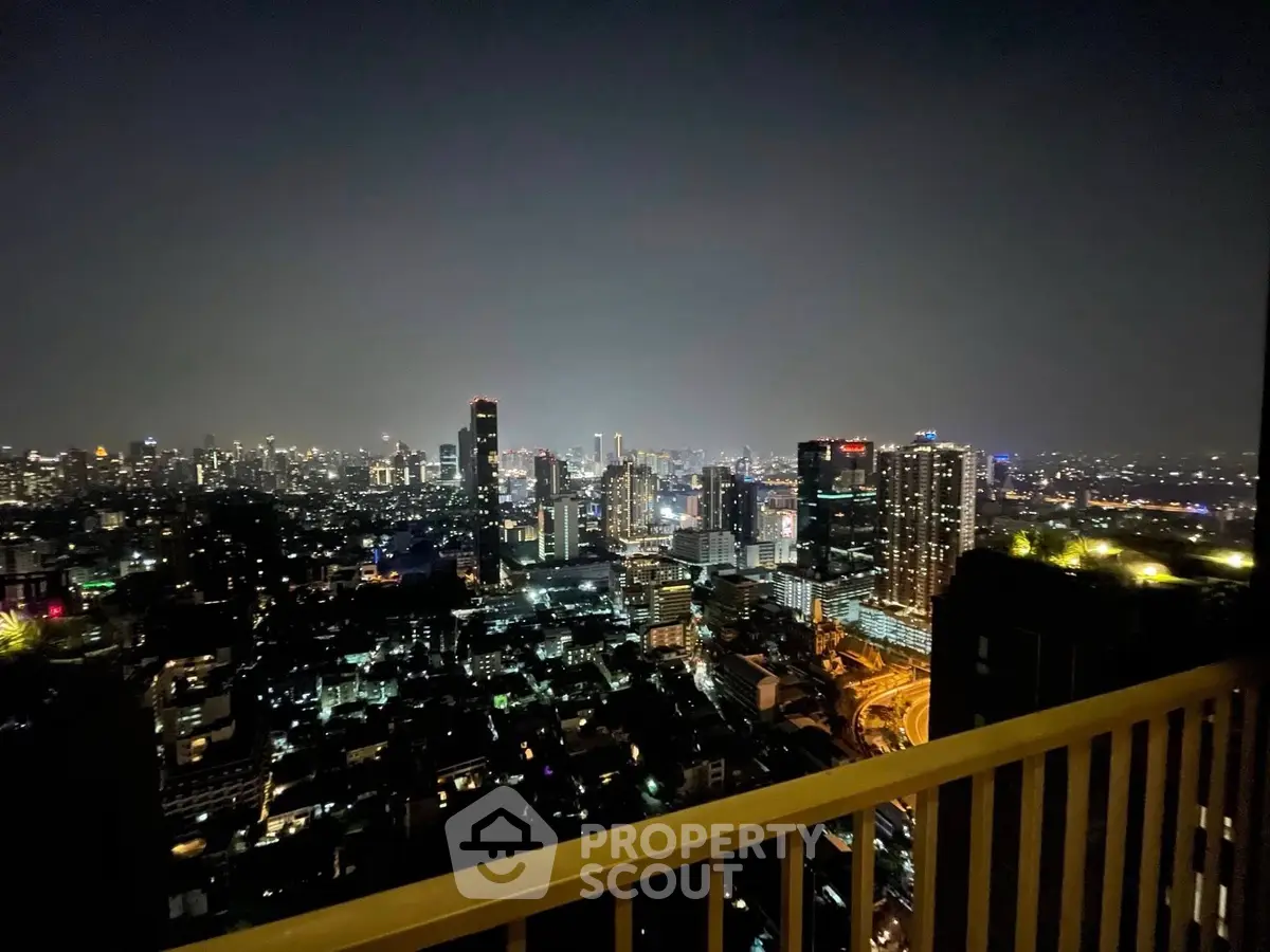 Stunning city skyline view from a high-rise balcony at night, showcasing vibrant urban lights.