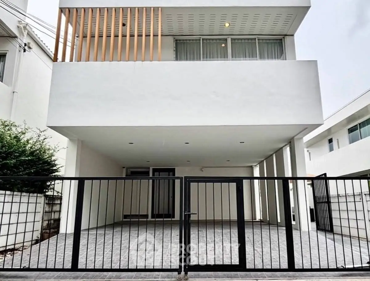 Modern minimalist white house exterior with gated entrance and spacious driveway.
