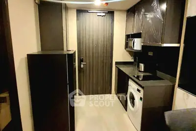 Modern kitchen with sleek cabinets, washing machine, and microwave in compact layout.
