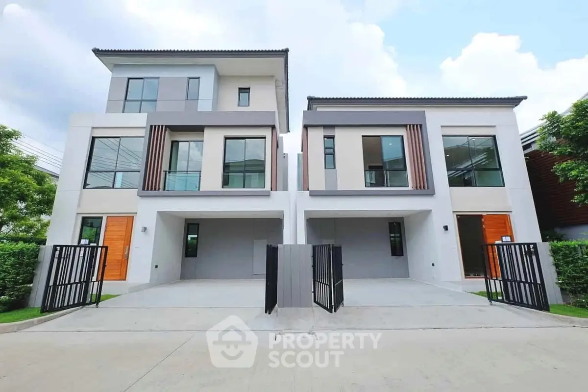 Modern twin townhouses with sleek design and spacious driveways in a serene neighborhood.