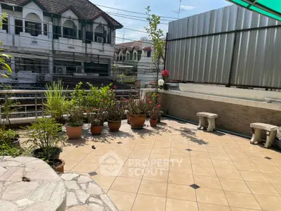 Spacious tiled balcony with potted plants and seating area, perfect for relaxation.