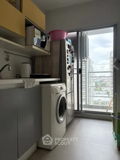 Modern kitchen with washing machine and balcony view in high-rise apartment