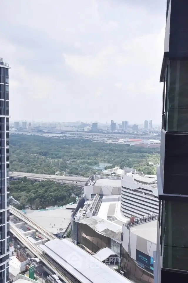Stunning cityscape view from high-rise building with lush greenery and modern architecture.