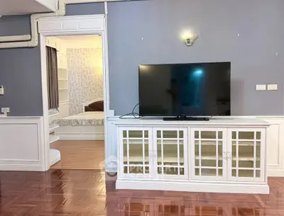 Spacious living room with elegant TV cabinet and glimpse of cozy bedroom