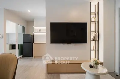 Modern living room with sleek TV setup and stylish kitchen area