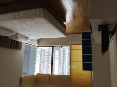 Spacious bedroom with large window offering city views and modern furnishings.