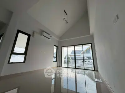 Spacious modern living room with high ceiling and large windows leading to a balcony.