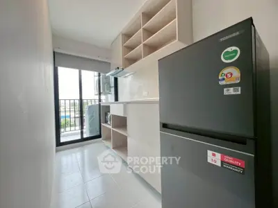 Modern kitchen with sleek fridge and ample storage, featuring a bright balcony view.