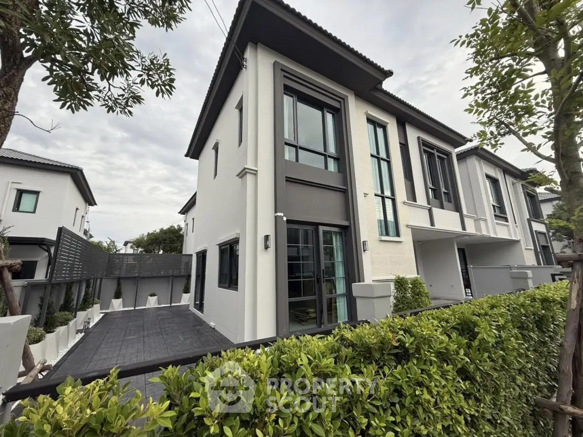 Modern two-story house with sleek design and lush greenery