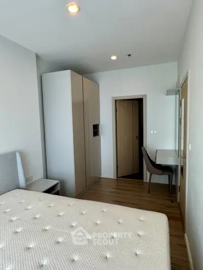 Modern bedroom with sleek furniture and wooden flooring, featuring a comfortable bed and a stylish desk area.