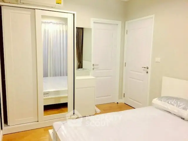 Bright and cozy bedroom with mirrored wardrobe and modern decor.