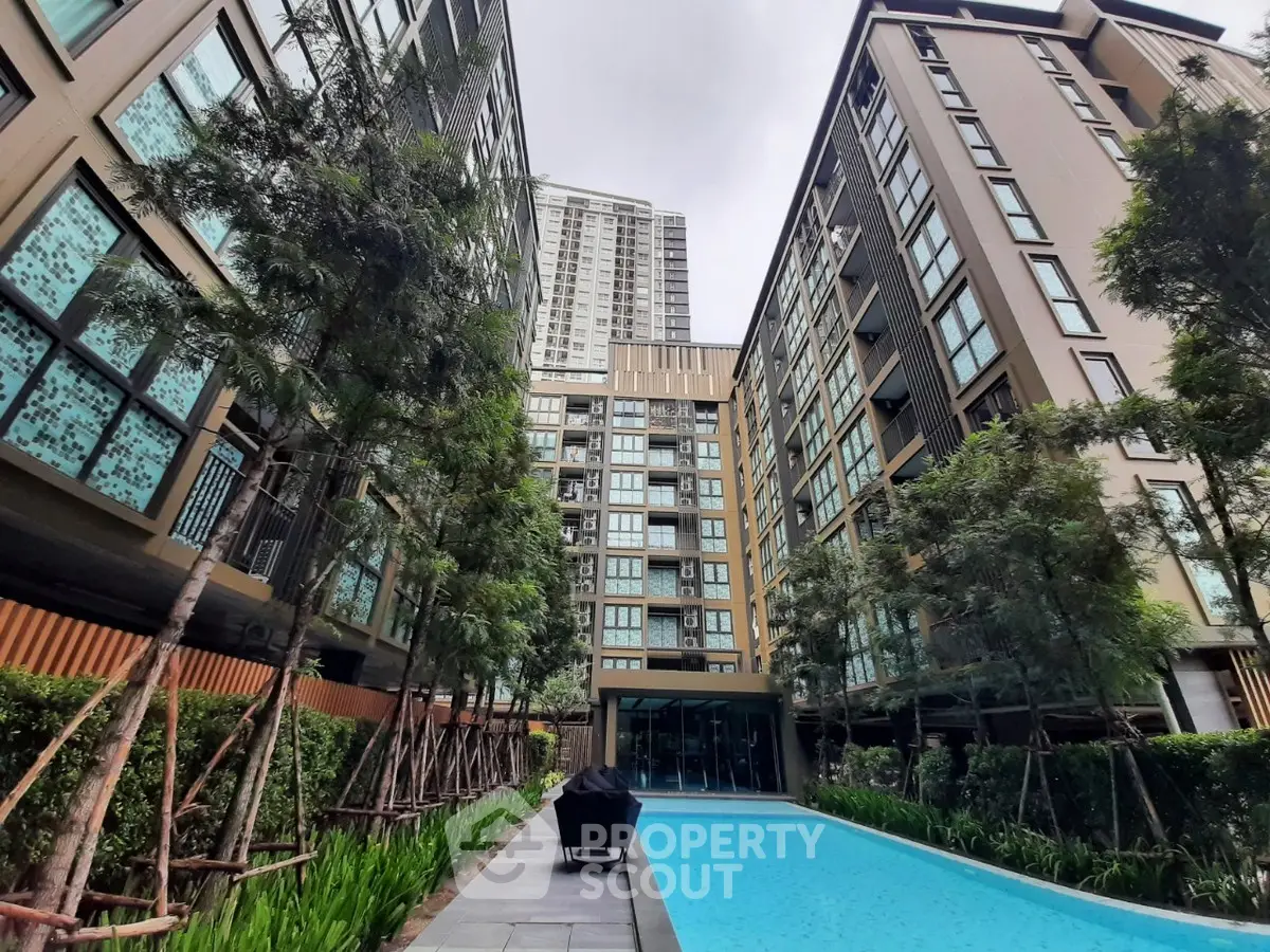 Modern apartment complex with pool and lush greenery, offering urban living with serene outdoor amenities.