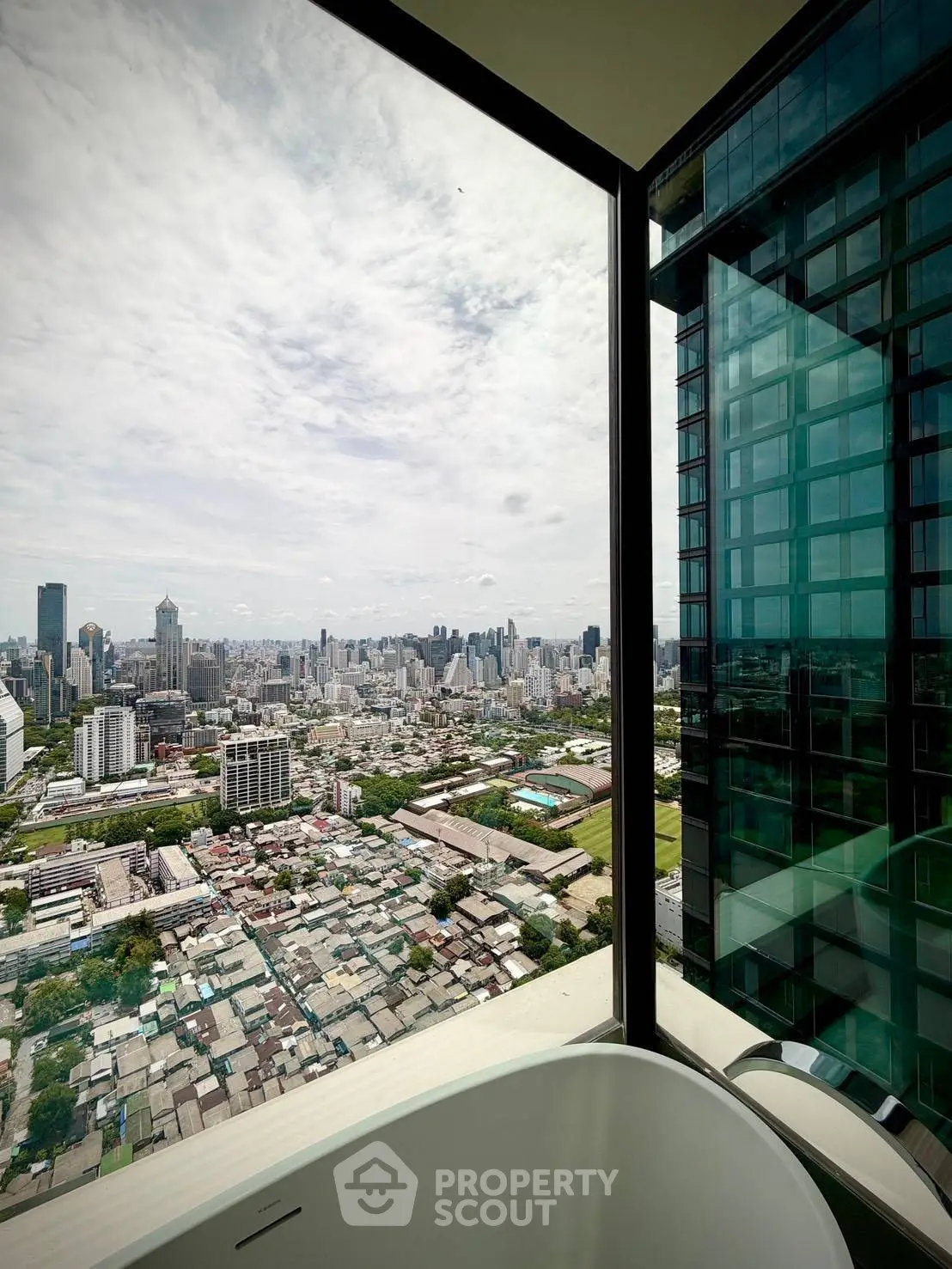 Stunning cityscape view from a modern high-rise apartment with floor-to-ceiling windows.