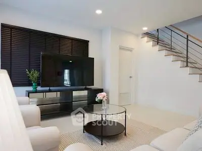 Modern living room with sleek TV setup and stylish staircase