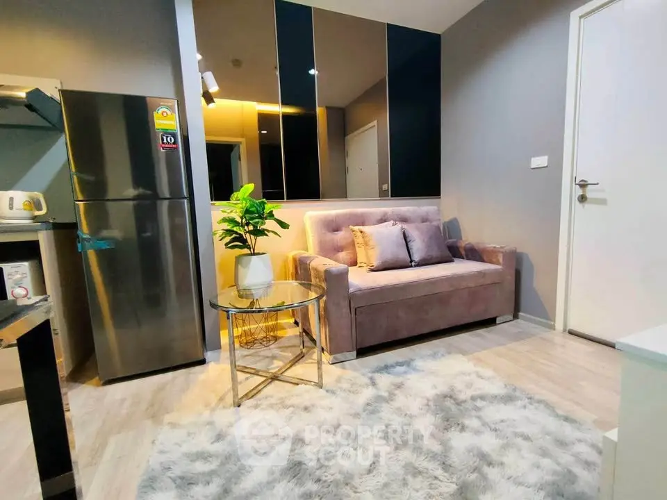 Modern living room with plush sofa, stylish decor, and sleek kitchen appliances.