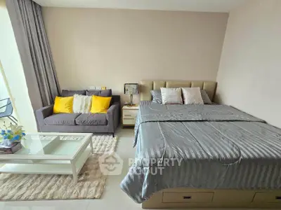 Modern bedroom with cozy seating area and stylish decor, featuring a plush bed and elegant coffee table.