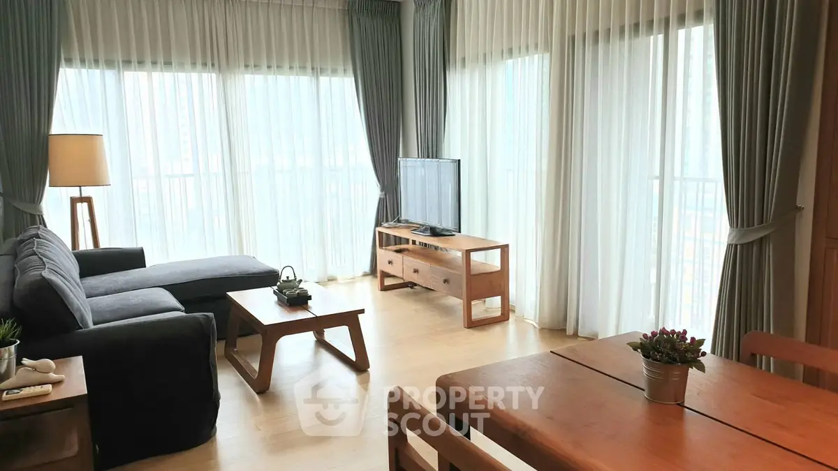 Spacious living room with large windows and modern wooden furniture