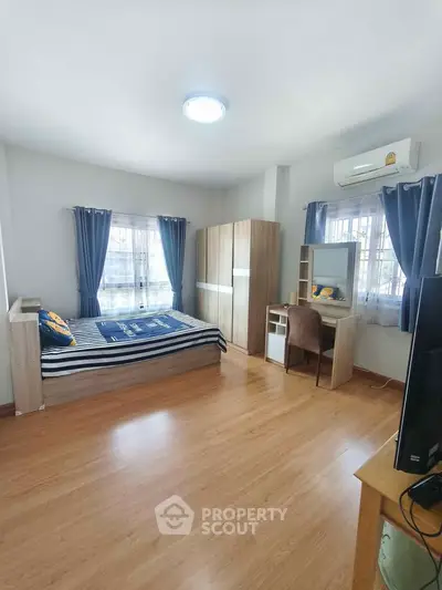 Spacious bedroom with modern furniture and natural light, featuring a cozy study area.