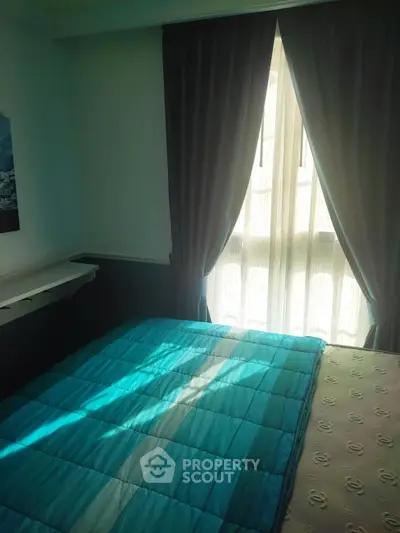 Cozy bedroom with natural light and elegant curtains, featuring a comfortable bed and stylish decor.