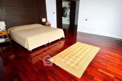 Spacious bedroom with elegant wooden flooring and cozy decor