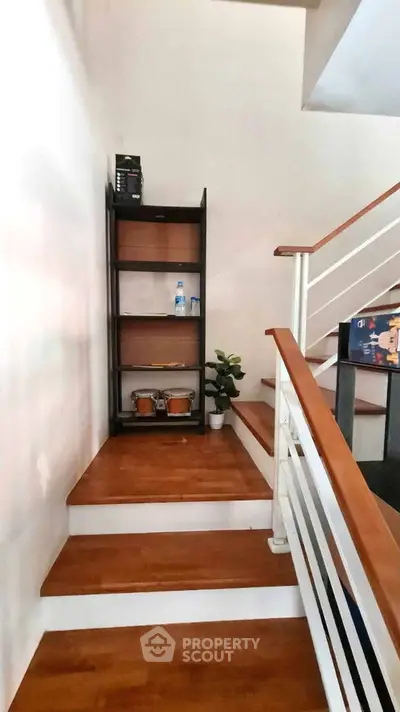 Stylish wooden staircase with modern railing and decorative shelf in a contemporary home