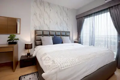 Elegant bedroom with modern decor and large window offering city views.