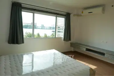 Bright bedroom with large window offering stunning river view, featuring air conditioning and minimalist decor.