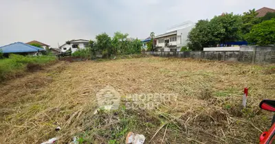 Vacant land plot in suburban area with surrounding houses and greenery.