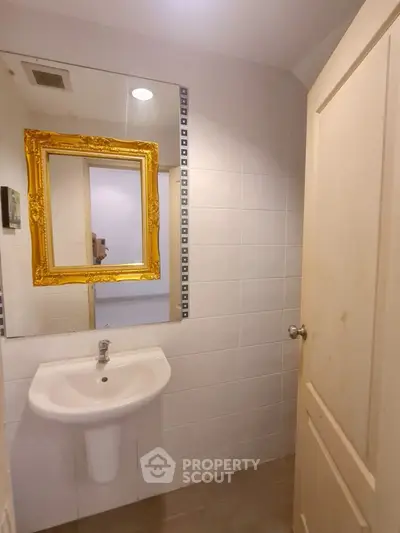 Charming bathroom with elegant gold-framed mirror and modern sink in cozy apartment.