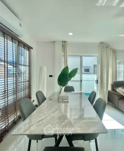 Modern dining area with marble table and stylish chairs in a bright, airy living space.