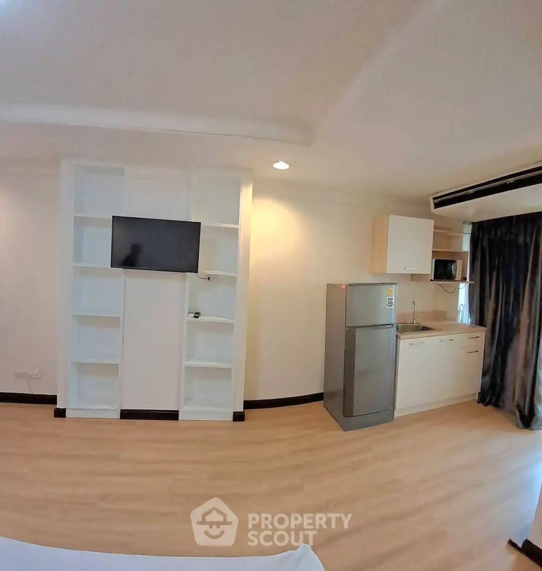 Modern studio apartment with built-in shelves and compact kitchen area