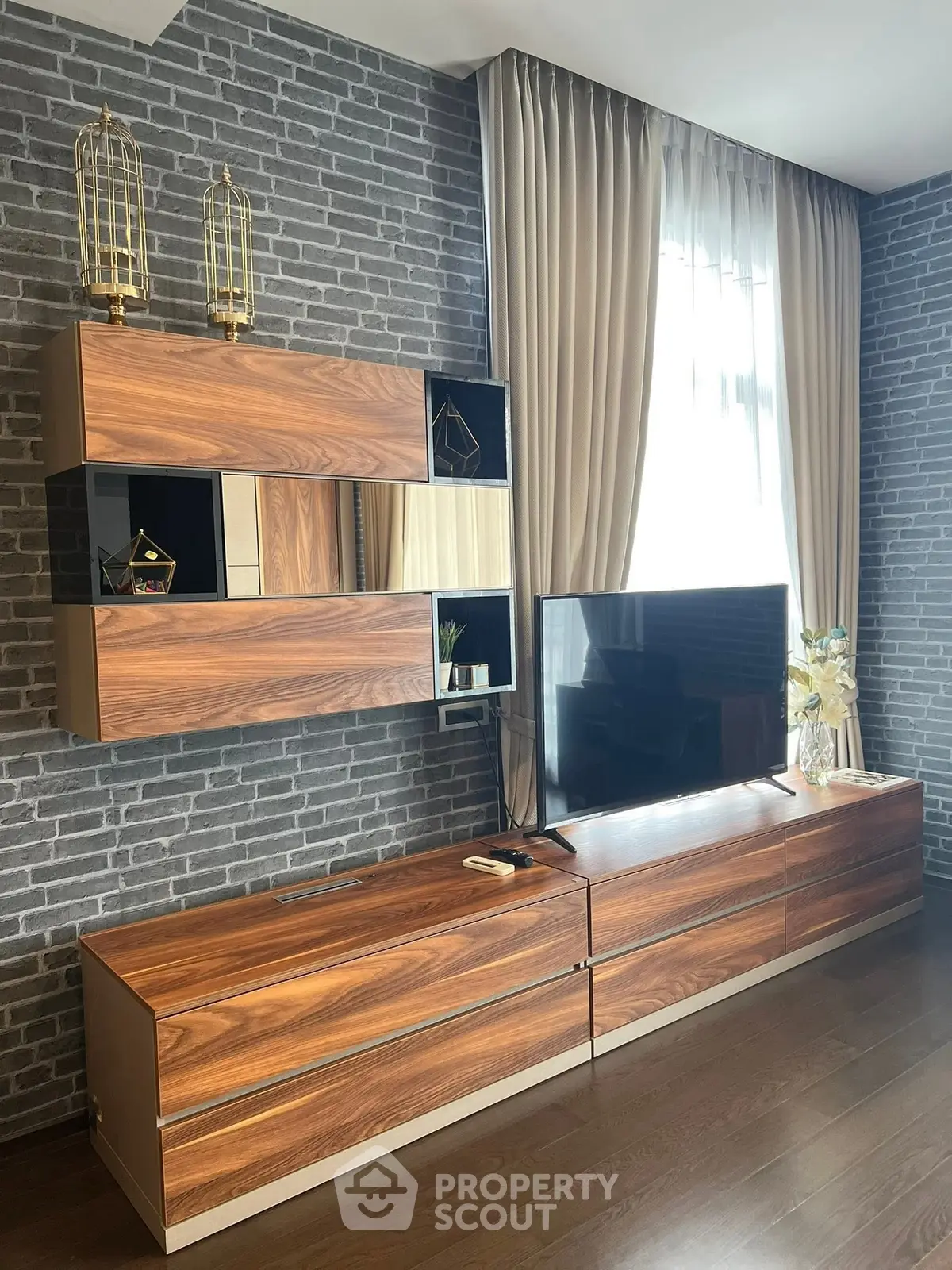 Modern living room with stylish wooden furniture and large TV, featuring elegant brick wall and floor-to-ceiling curtains.