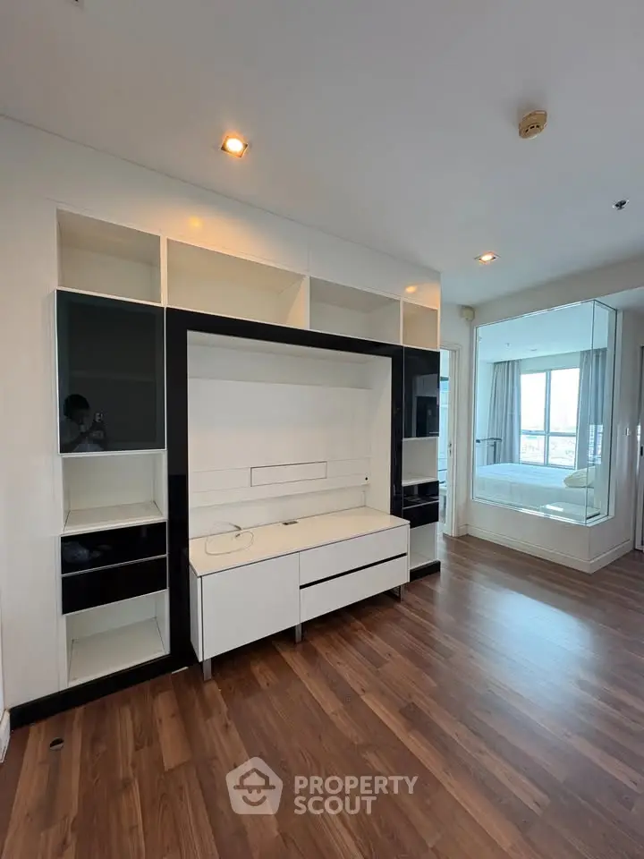 Modern living room with sleek built-in shelving and hardwood floors in a high-rise apartment.