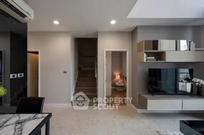 Modern living room with stylish decor and open layout, featuring a staircase and cozy bedroom view.