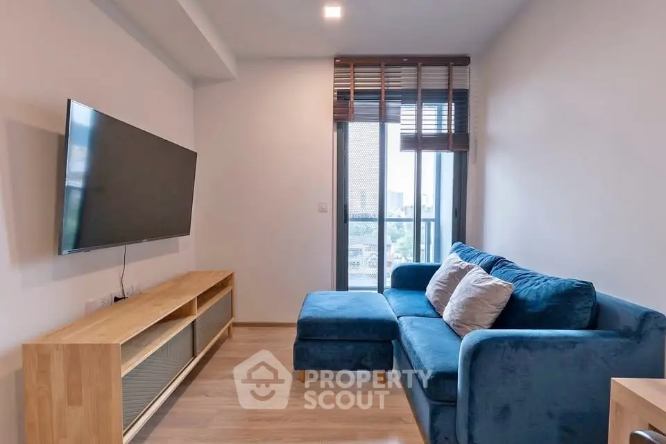 Modern living room with blue sofa and wall-mounted TV in a cozy apartment.