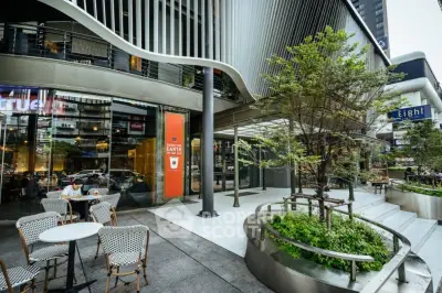 Modern commercial building exterior with outdoor seating and lush greenery.
