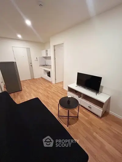 Modern living room with sleek furniture and compact kitchen in open layout apartment.