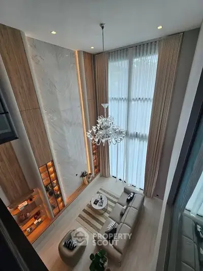 Luxurious high-ceiling living room with elegant chandelier and floor-to-ceiling windows