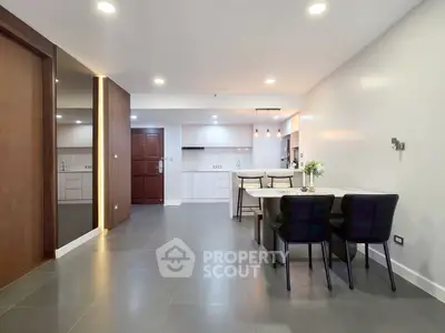 Spacious modern living area with open kitchen and dining space, featuring sleek design and ample lighting.
