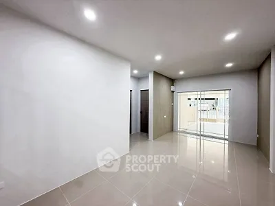 Spacious modern living room with sleek tile flooring and sliding glass doors leading to a balcony.