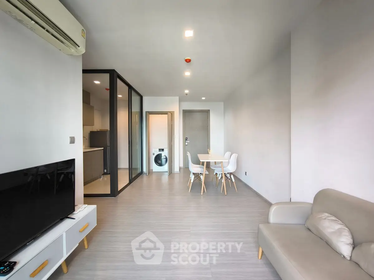 Modern living room with sleek furniture and open kitchen layout, featuring a washing machine.