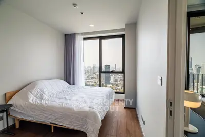 Modern bedroom with city view, featuring large windows and minimalist decor.