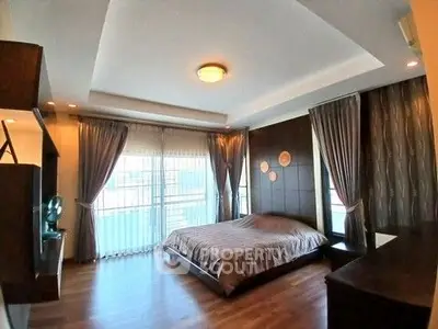 Spacious bedroom with modern decor and large windows for natural light.