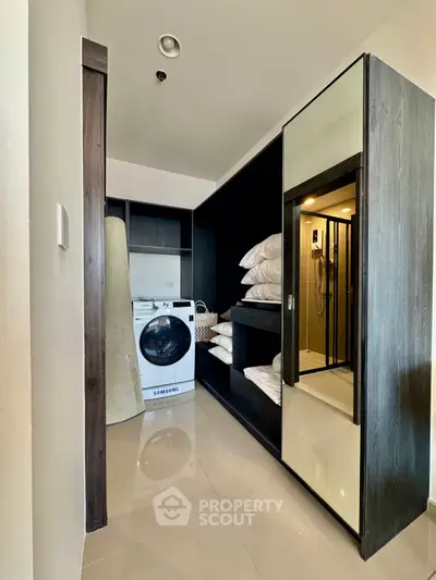 Modern laundry area with sleek storage and washing machine in stylish apartment