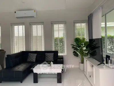 Modern living room with sleek black sofa, large windows, and stylish decor