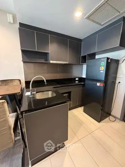 Modern kitchen with sleek black cabinets and appliances in a stylish apartment.